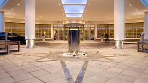 A spacious lobby with a central water feature, large windows, and a modern architectural design. - Southern Sun Cape Town Waterfront (Cape Town)