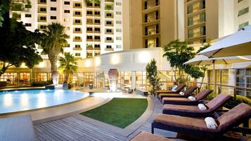 Alberca al aire libre, sombrillas en la alberca y camastros