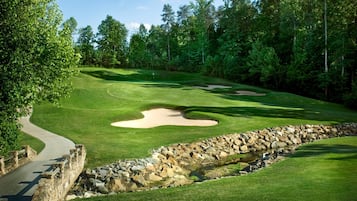 Un campo da golf con un muro in pietra, un elemento decorativo d'acqua e un manto erboso ben curato.