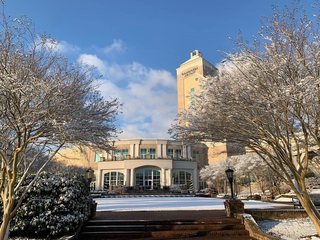 A building with a central entrance, a tower, and snow-covered trees.