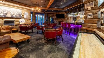 A bar area with wooden walls, red leather chairs, and a bar counter with a television above it.