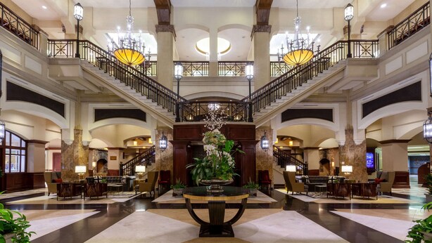 A grand lobby with a central fountain, multiple staircases, and elegant chandeliers. - Grandover Resort & Spa, a Wyndham Grand Hotel (Greensboro)