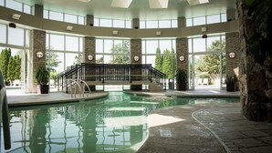 A large indoor swimming pool with a central staircase and stone walls. - Grandover Resort & Spa, a Wyndham Grand Hotel (Greensboro)