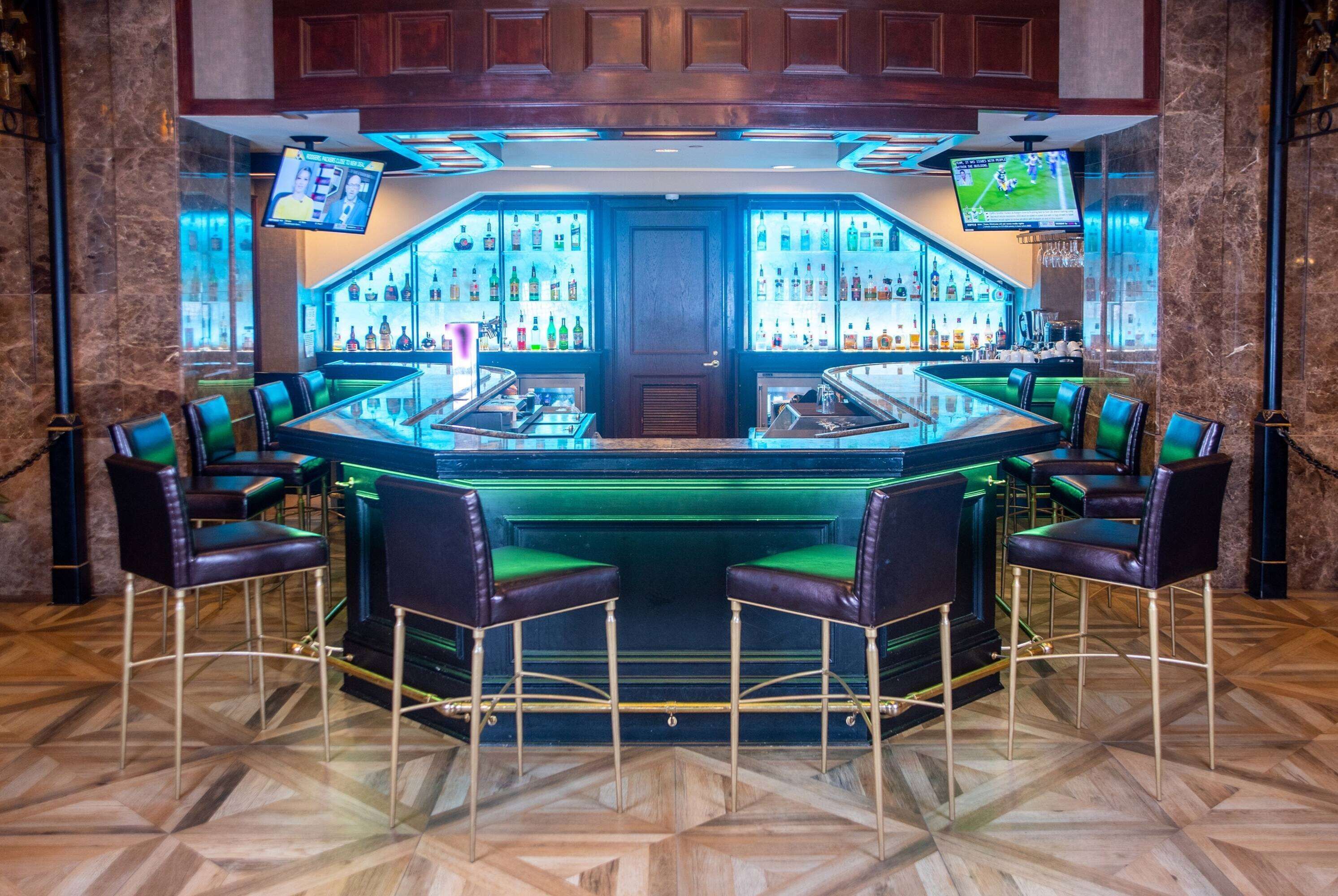 A bar area with a central counter, multiple seating options, and a large display screen above the bar.