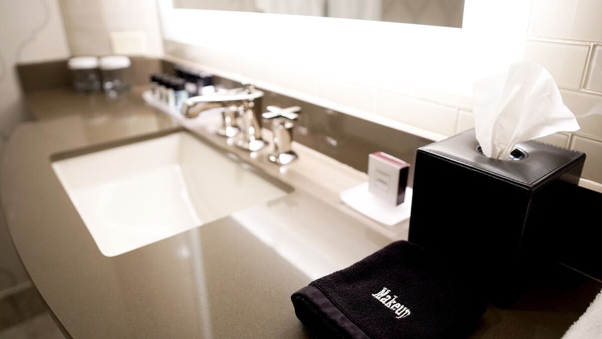 A bathroom with a modern sink, a tissue box, and a towel.
