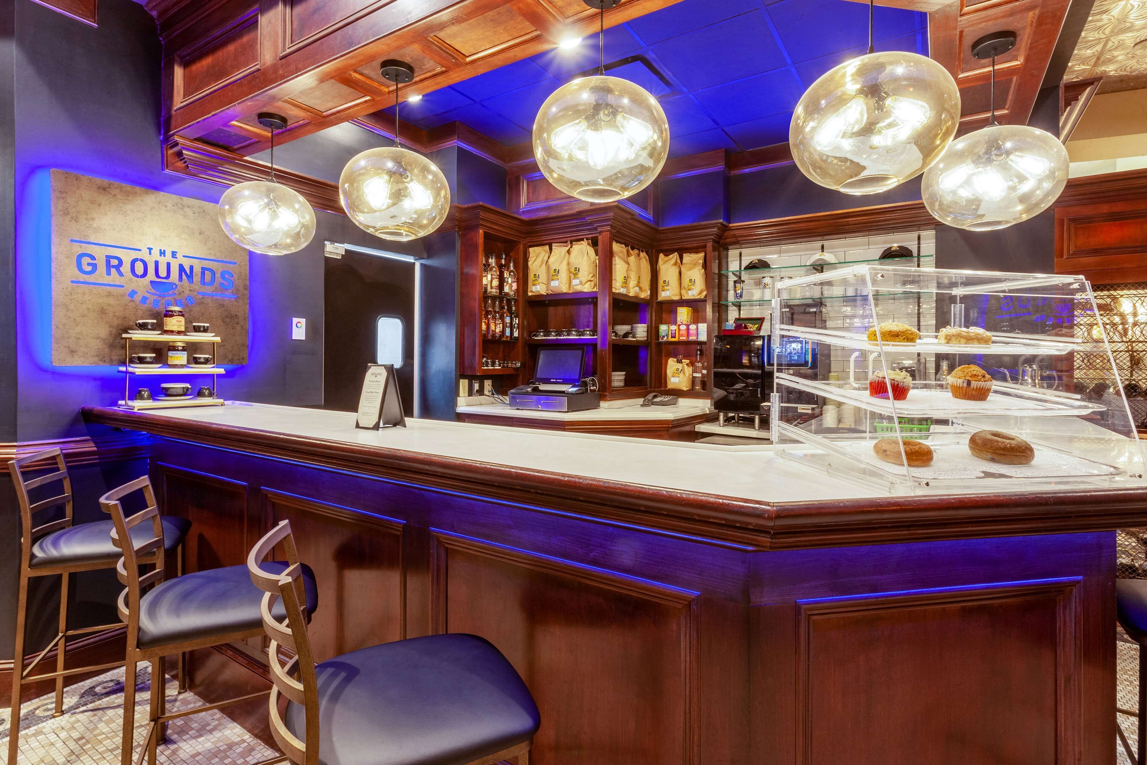 A bar area with a counter, stools, and a display case with pastries.