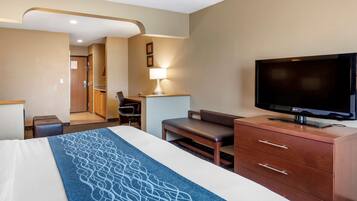 A hotel room with a bed, a TV, a desk, and a lamp.