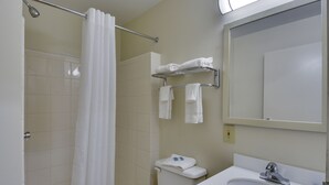 A bathroom with a shower, toilet, sink, and towel rack. - HomeTowne Studios by Red Roof Austin (Austin)