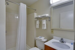 A bathroom with a shower, toilet, sink, and towel rack. - HomeTowne Studios by Red Roof Austin (Austin)