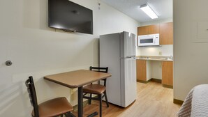 A compact kitchen with a refrigerator, microwave, and a small dining area with a table and two chairs.