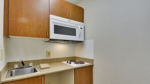 A compact kitchen with a built-in microwave, a sink, and a small countertop. - HomeTowne Studios by Red Roof Austin (Austin)