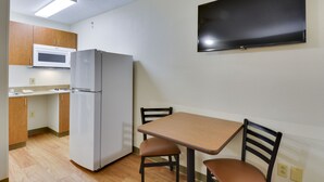 A compact kitchen with a microwave, refrigerator, and a flat-screen TV mounted on the wall. - HomeTowne Studios by Red Roof Austin (Austin)