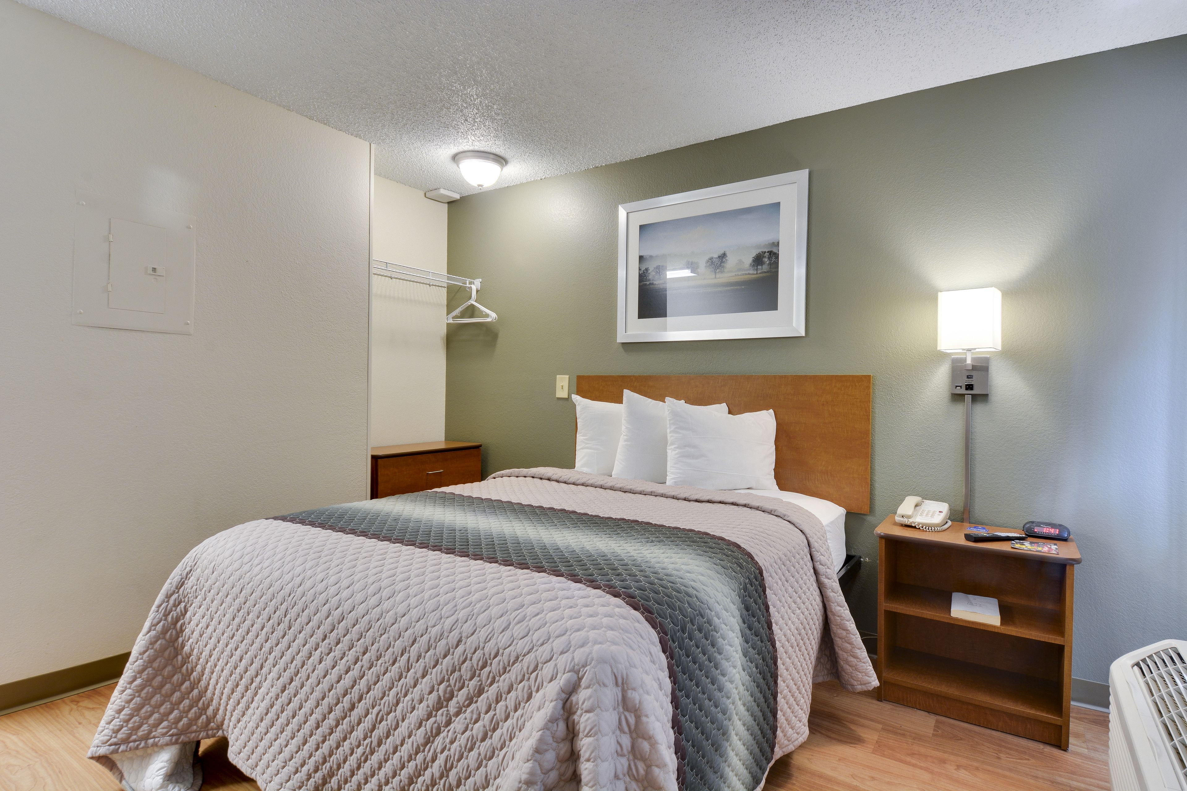 A neatly arranged hotel room with a bed, bedside table, and a wall-mounted picture.
