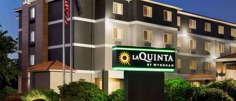 Un hotel de varios pisos con un llamativo letrero de La Quinta by Wyndham.