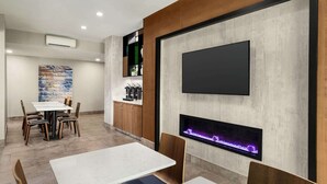 A modern dining area with a fireplace, a mounted television, and a stone accent wall. - La Quinta Inn & Suites by Wyndham Salem OR (Salem)