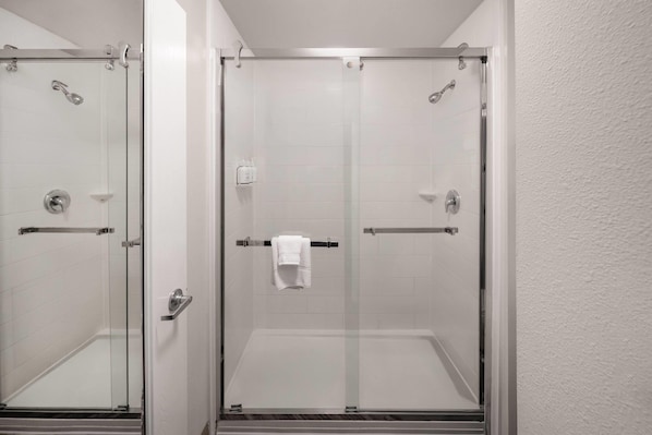 A glass-enclosed shower with a white towel on the door handle.