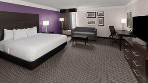 Ein Hotelzimmer mit einem großen Bett, einer Couch, einem Schreibtisch und einem Fernseher.