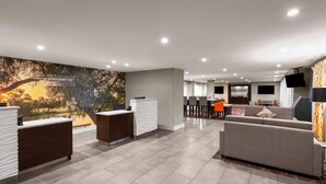 Eine moderne Hotelhalle mit Rezeption, Sitzgelegenheiten und einem großen Wandbild.