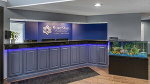 Un mostrador de recepción con una decoración azul y blanca, un acuario grande y un letrero de SureStay PLUS HOTEL by BEST WESTERN.