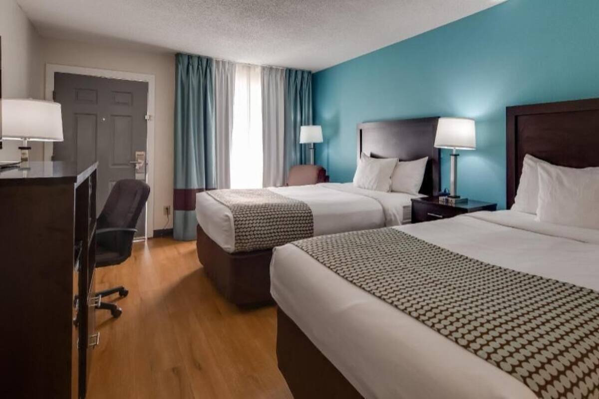 Een hotelkamer met twee bedden, een bureau, een stoel en een deur.