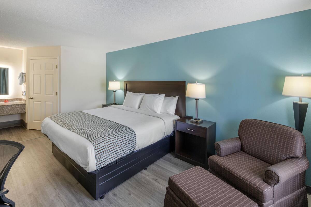 Een hotelkamer met een bed, nachtkastjes met lampen, een stoel en een bureau met een stoel.