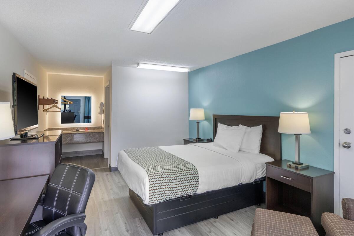 Een hotelkamer met een bed, nachtkastjes, een bureau, een stoel en een spiegel.