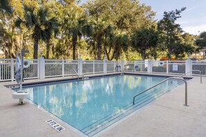 A rectangular pool with a white fence and metal railings, surrounded by palm trees and a clear sky. - HOM Hotel Gainesville, SureStay Collection by Best Western (Gainesville)