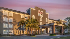 A hotel with a modern facade, a covered entrance, and a palm tree in front. - HOM Hotel Gainesville, SureStay Collection by Best Western (Gainesville)