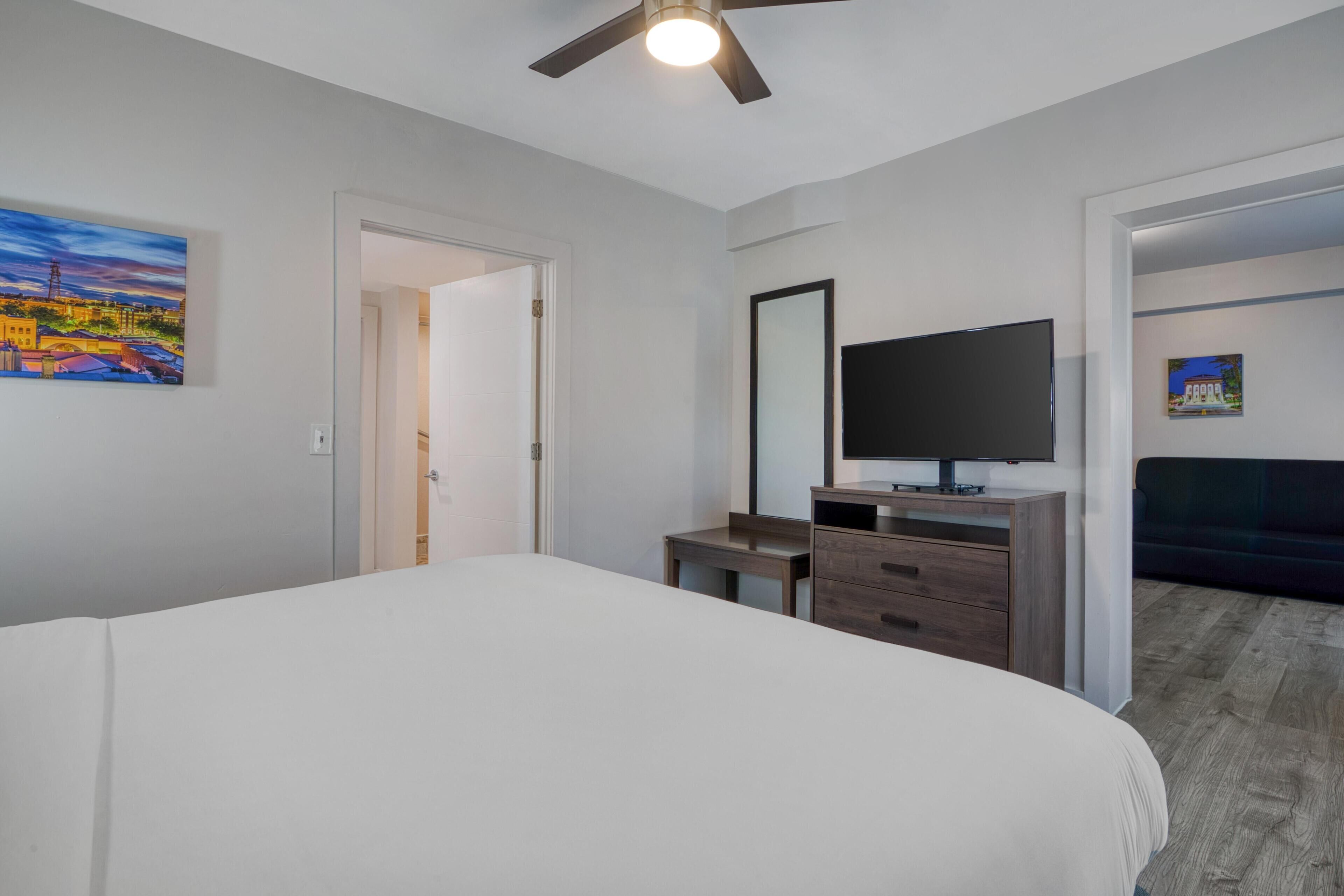 Quarto com cama, escrivaninha, televisão e obras de arte nas paredes.