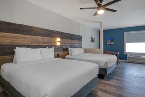 A hotel room with two beds, a ceiling fan, a wall-mounted light, and a window with blinds. - HOM Hotel Gainesville, SureStay Collection by Best Western (Gainesville)