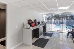 A modern reception area with a counter, fire extinguishers, and a view of a swimming pool through glass doors. - HOM Hotel Gainesville, SureStay Collection by Best Western (Gainesville)