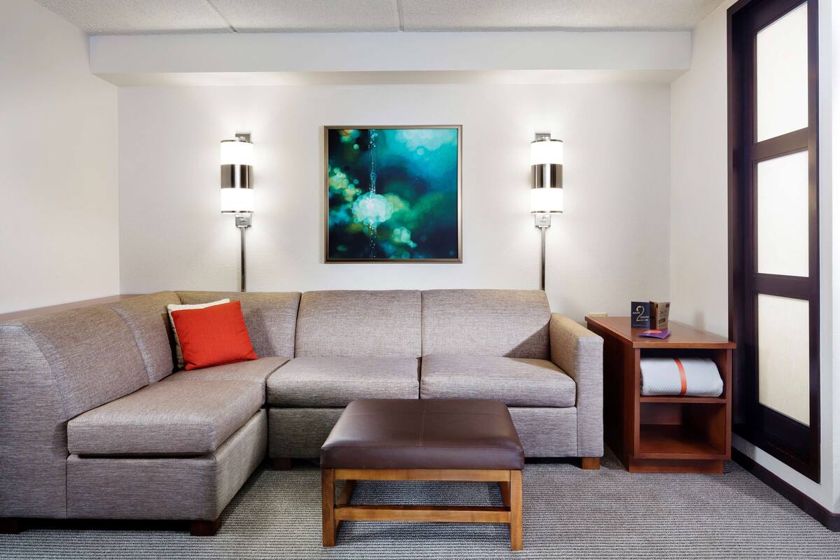 A modern living room with a gray sectional sofa, a wooden coffee table, and two wall-mounted floor lamps.