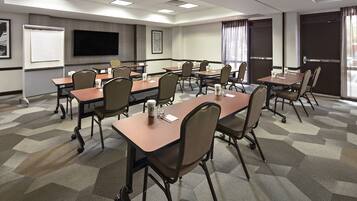 A conference room with a large table, chairs, a whiteboard, a flat-screen TV, and a carpeted floor.