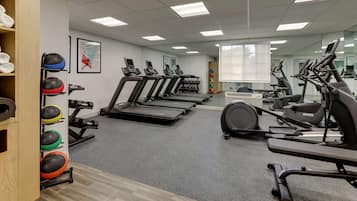 Un gimnasio con cintas de correr, elípticas y una variedad de pelotas de ejercicio.