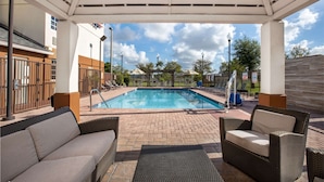 Un espace extérieur abrité avec une piscine, des chaises longues et une terrasse en briques.