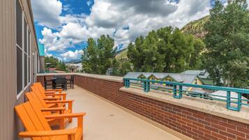 Un espace patio avec des chaises orange, un mur de briques et une vue sur des maisons et des arbres.