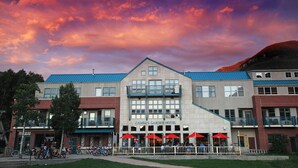 A hotel with a prominent entrance, a lift ticket office, and outdoor seating with red umbrellas. - Camel's Garden Hotel (Telluride)