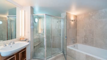 A modern bathroom with a glass-enclosed shower, a large bathtub, and a vanity with a sink.