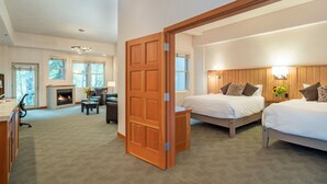 A modern bedroom with two beds, a fireplace, and a large window. - Camel's Garden Hotel (Telluride)