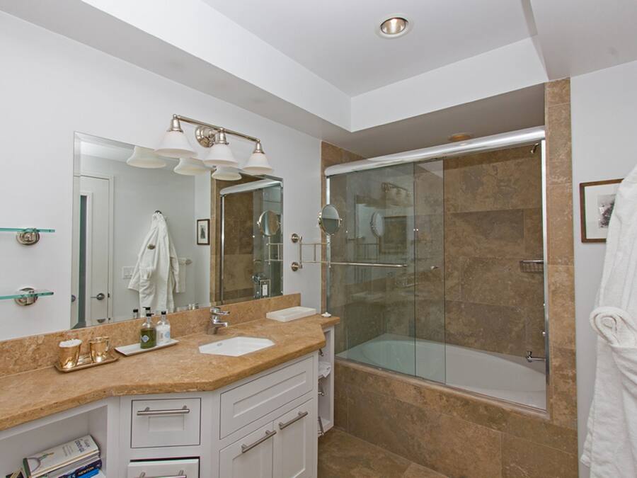 Une salle de bain moderne avec une douche à parois de verre, un meuble-lavabo avec un évier et un miroir, et un porte-serviettes.