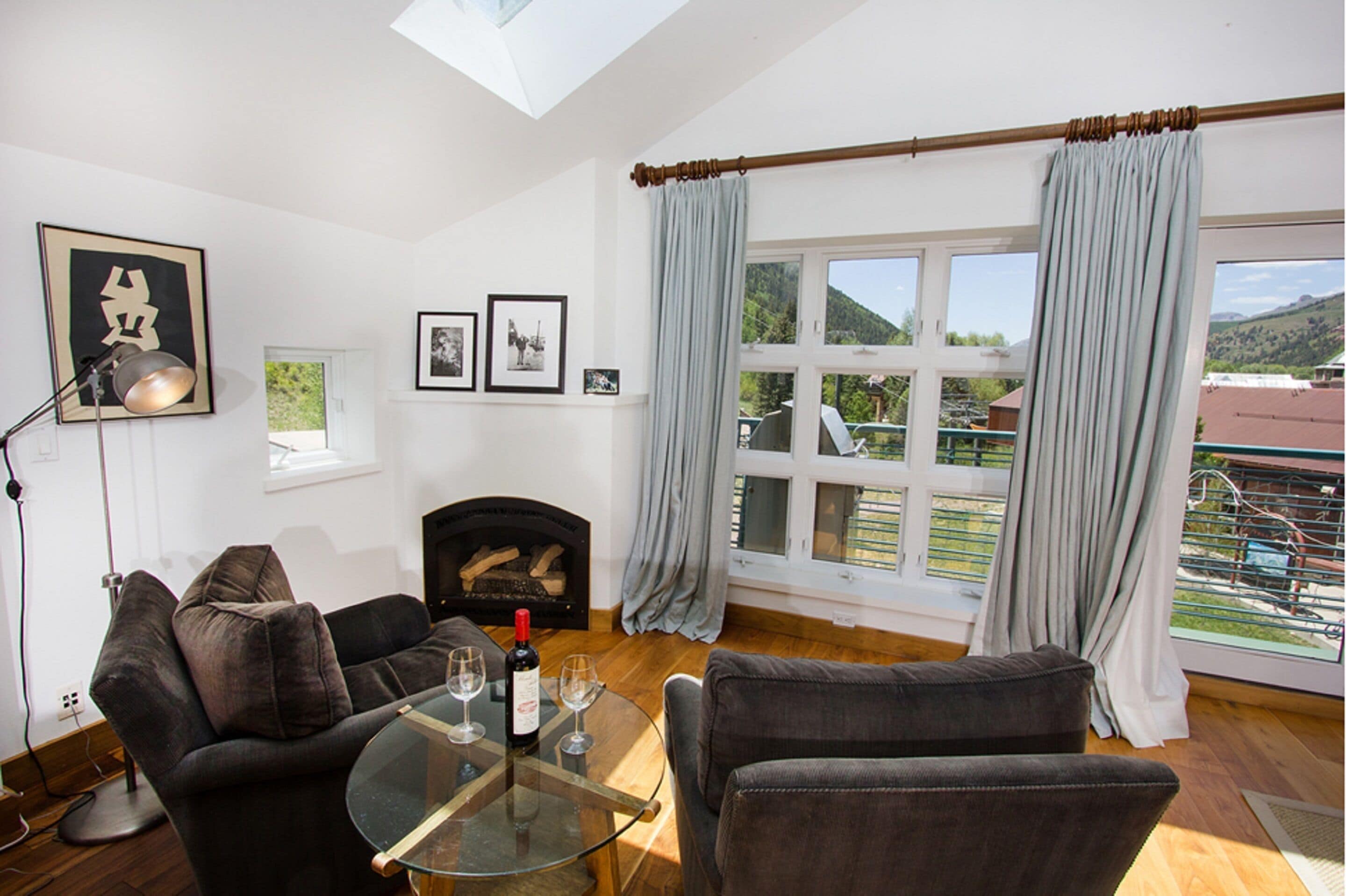 A living room with a fireplace, a sofa, a glass coffee table, and a view of the outdoors.