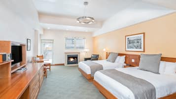 A hotel room with two beds, a TV, a fireplace, and a desk.