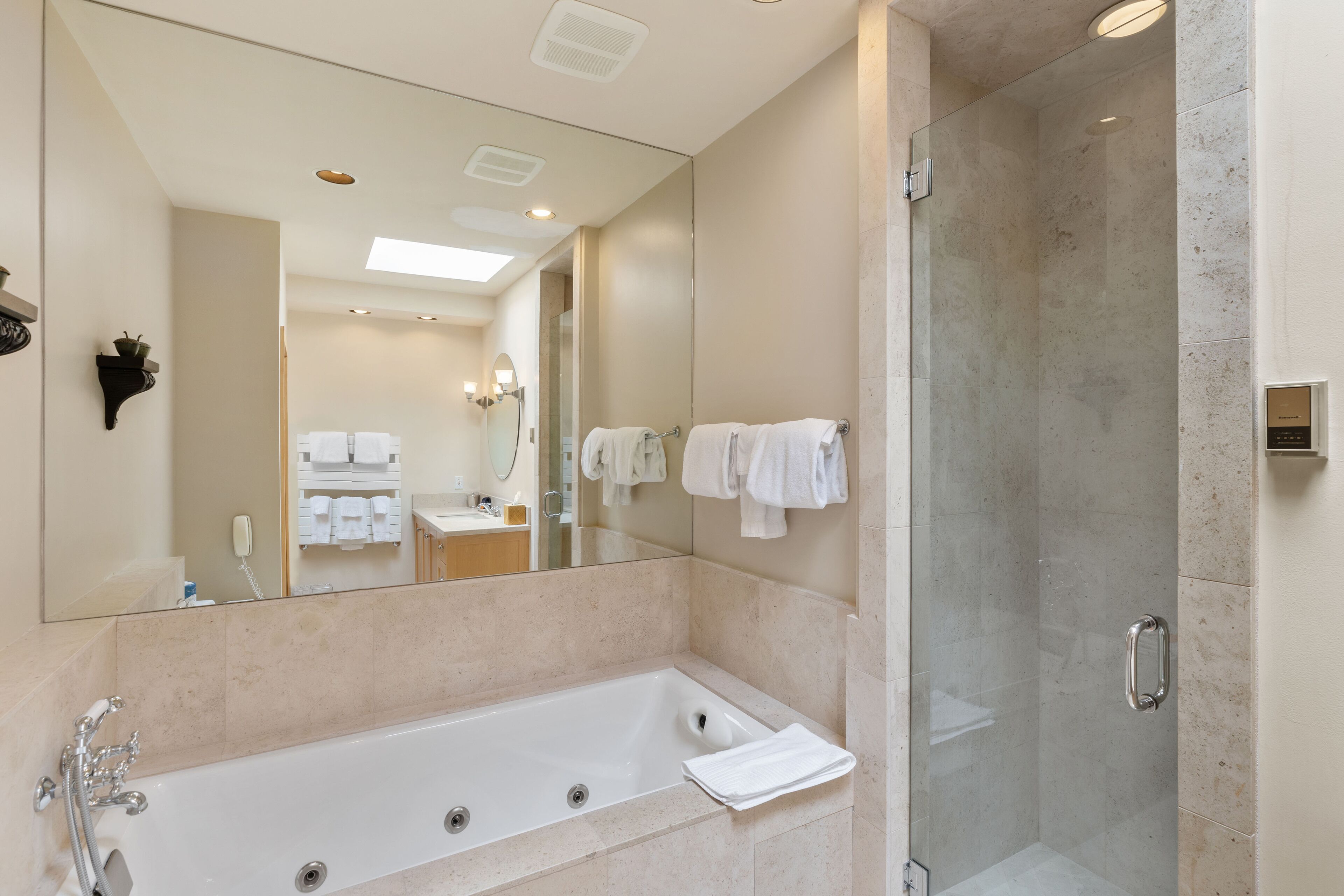 Un baño moderno con un espejo grande, una bañera y una ducha con mampara de vidrio.