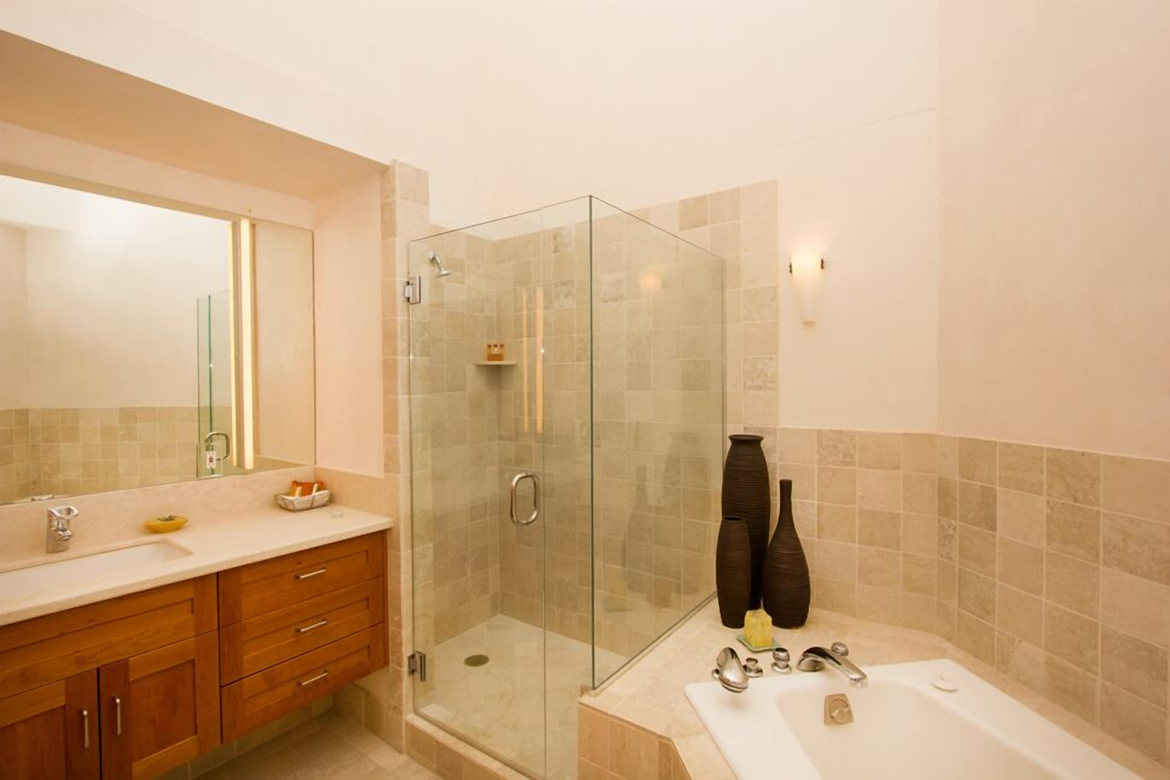 A modern bathroom with a glass-enclosed shower, a vanity with a mirror, and a bathtub.