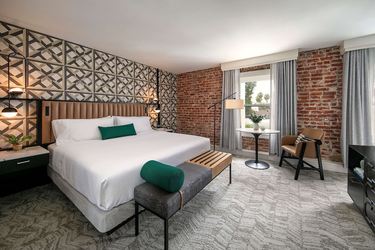 Ein modernes Hotelzimmer mit einem großen Bett, einem kleinen Tisch, einem Stuhl und einem Schreibtisch.