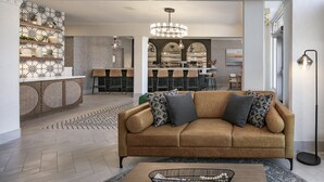 A modern living room with a sofa, a coffee table, and a bar area in the background.