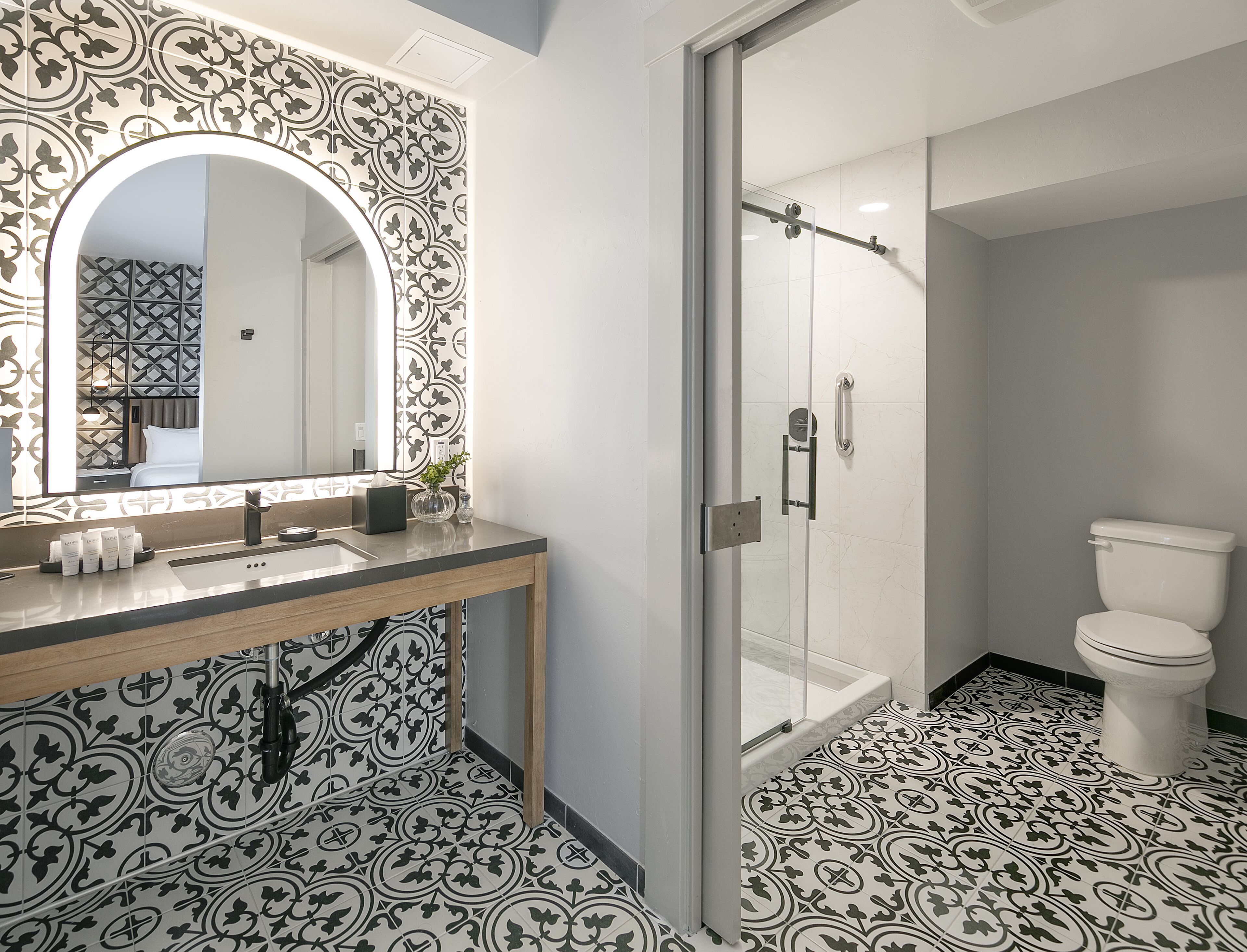 A modern bathroom with a large mirror, a shower, and a toilet.