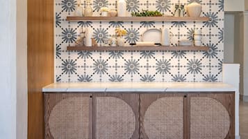Una cocina con salpicadero estampado, estantes de madera y un mueble de ratán.