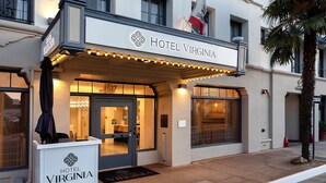 The exterior of Hotel Virginia with a prominent entrance, a flag, and a well-lit facade.