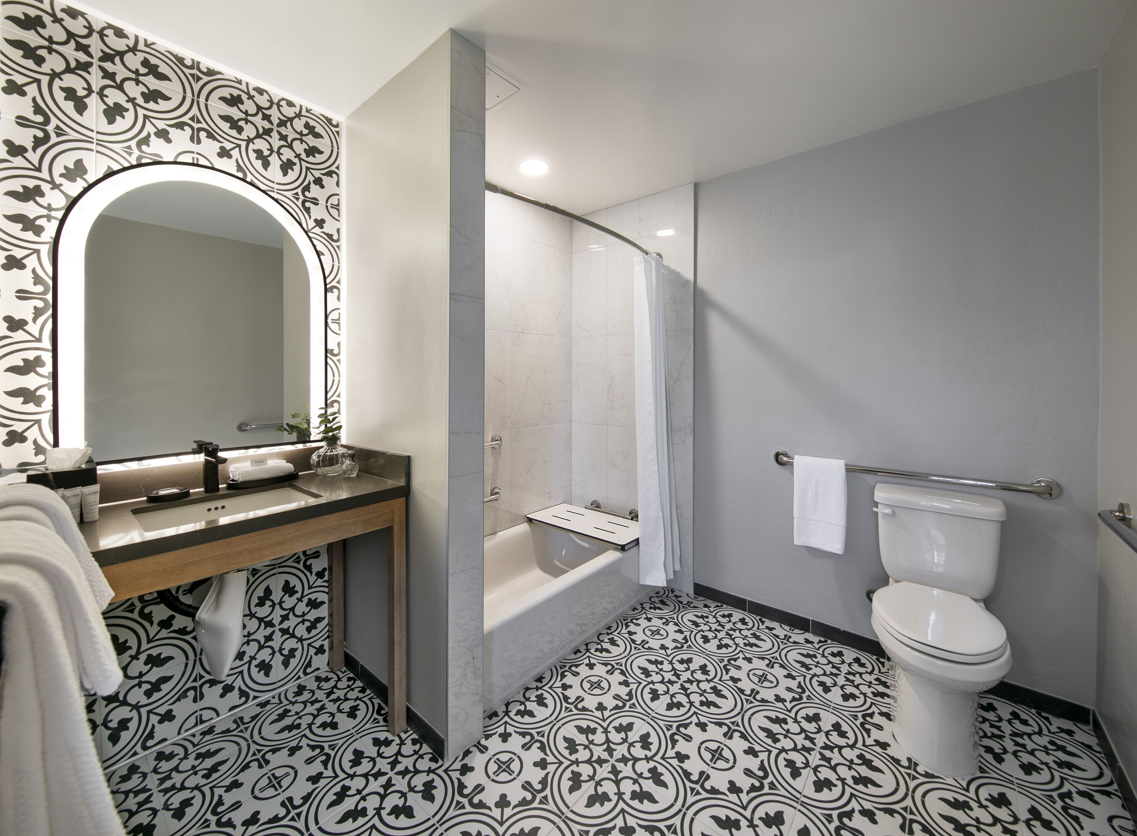 Un baño con un espejo grande, un lavabo con toallero, un inodoro y una zona de ducha.